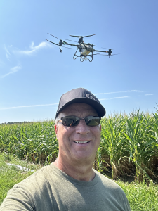 A selfie of author Fred Nichols with a drone flying in the blue sky.