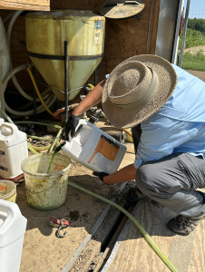 A person pouring product into a bucket.