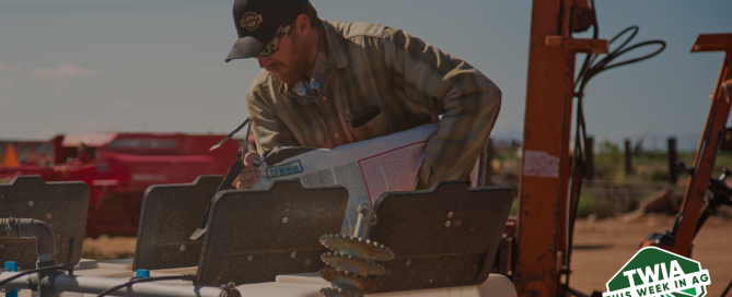 A nice photo of a farmer wearing a black Huma branded hat, pouring product in a tank.